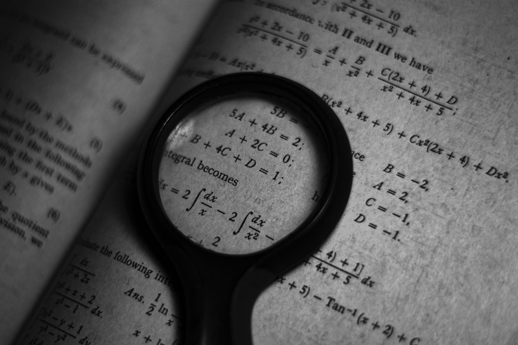Magnifying glass resting on a book with math equations